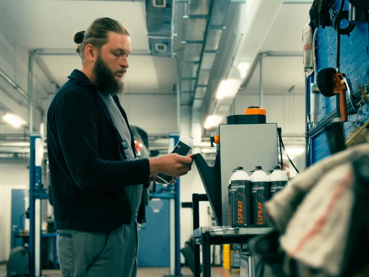 Mechanic with a RESPRAY™ bottle next to the RSB refill machine in the workshop